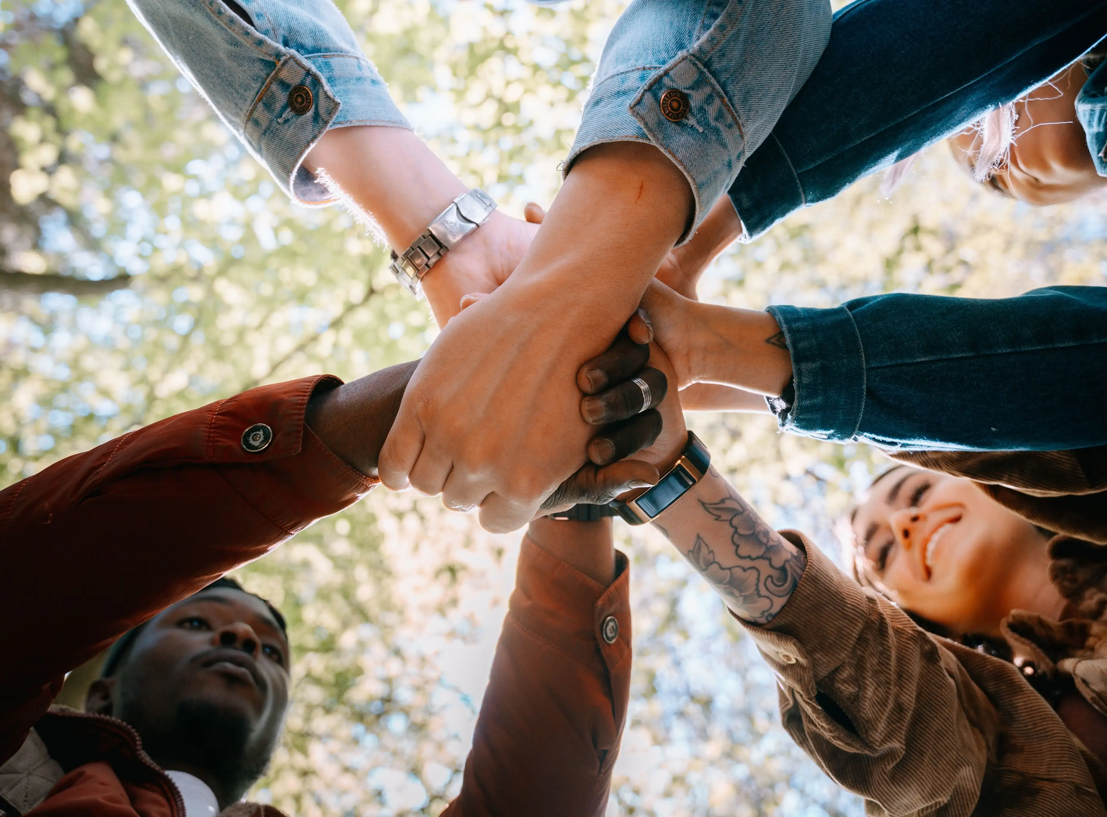 A circle of people placing their hands together to show shared support and community solidarity.