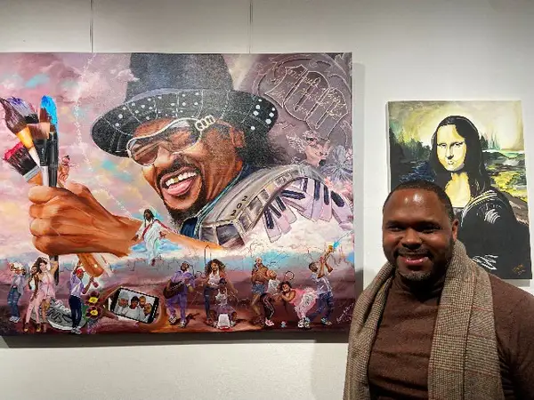 A recently returned PDS client stands beside his large mural on display at the Beauty Behind Bars exhibition.